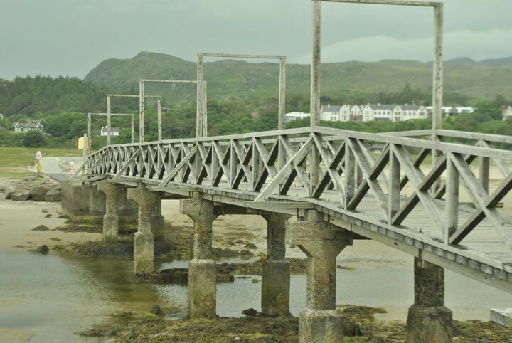 a quaint, long wooden bridge over the marshy area