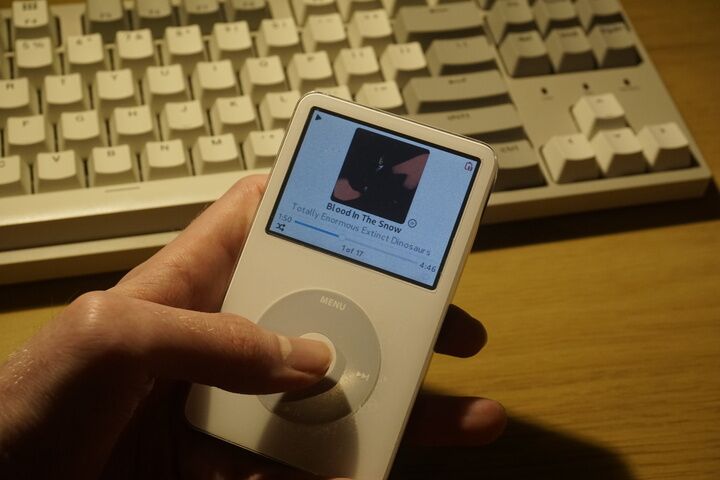 A white ipod classic, running rockbox. Playing music.