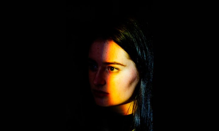 A portrait of a girl with light on half her face, to the side.