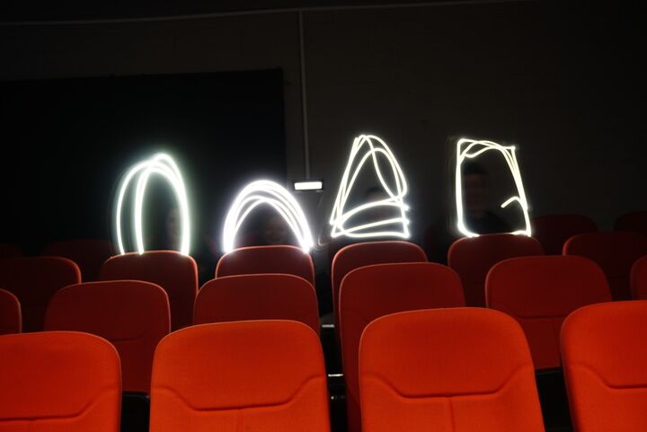 Various shapes of light drawn above cinema seats.